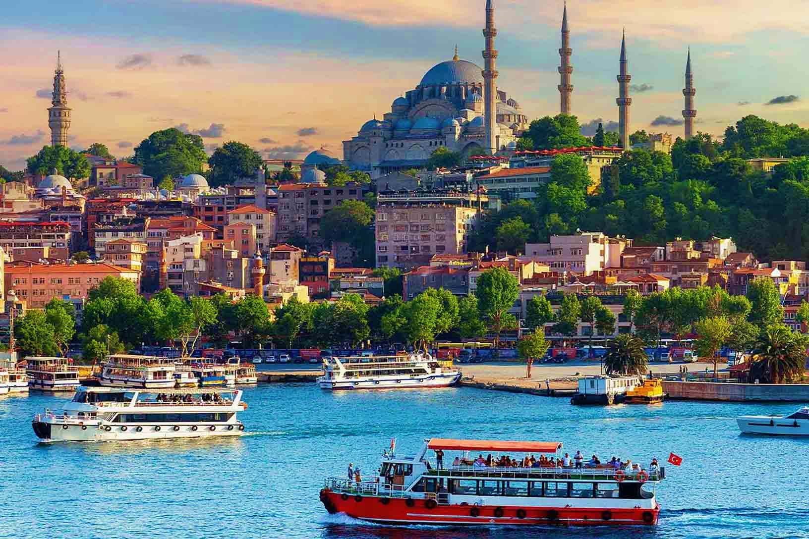 Istanbul skyline at sunset with Suleymaniye Mosque, Golden Horn waterway, and passenger ferries